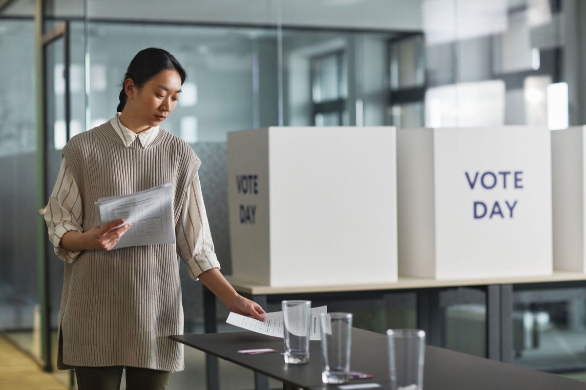 Urna eletrônica e cédulas de votação representando o processo eleitoral.